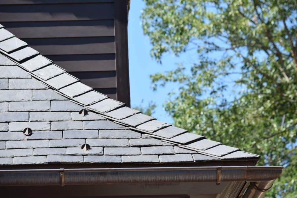 zoomed in photo of a slate roof ridge and corner with copper gutters