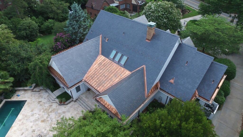 aerial photos of slate roof with copper details surrounded by green trees