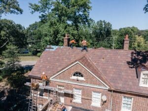 Roofers working installing a red clay tile roof
