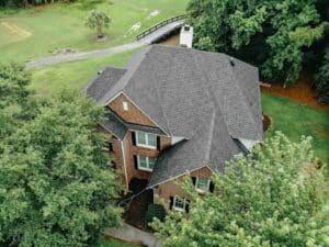 Aerial view of a gray shingle roof on a brick house on a golf course