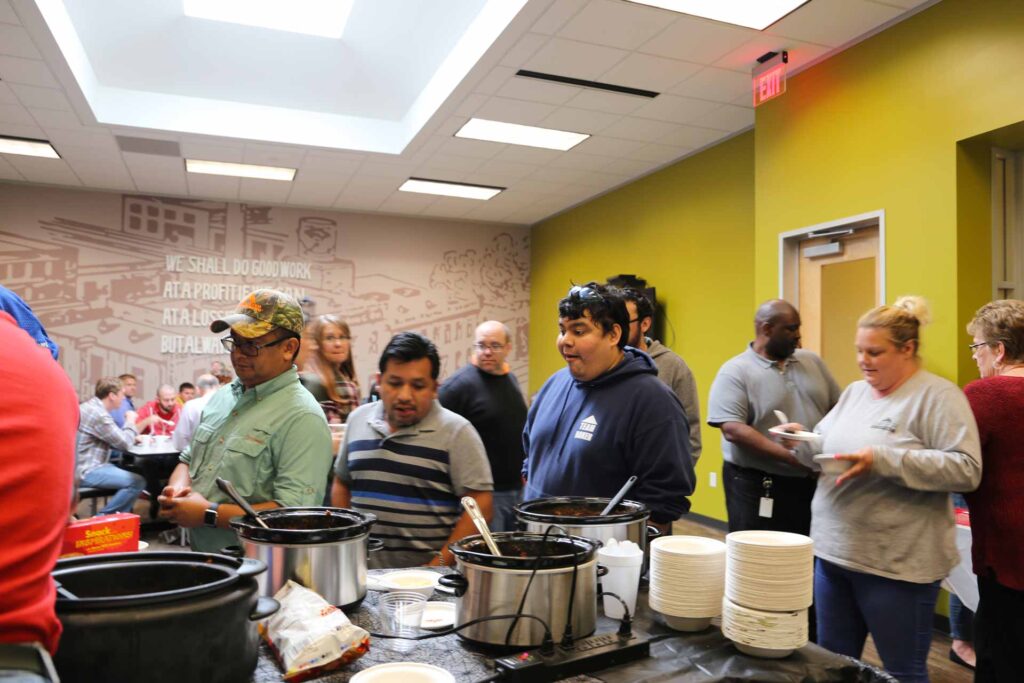 Employees in a corporate kitchen tasting different chili recipes
