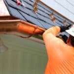 Baker roofing employee installing new copper gutters.