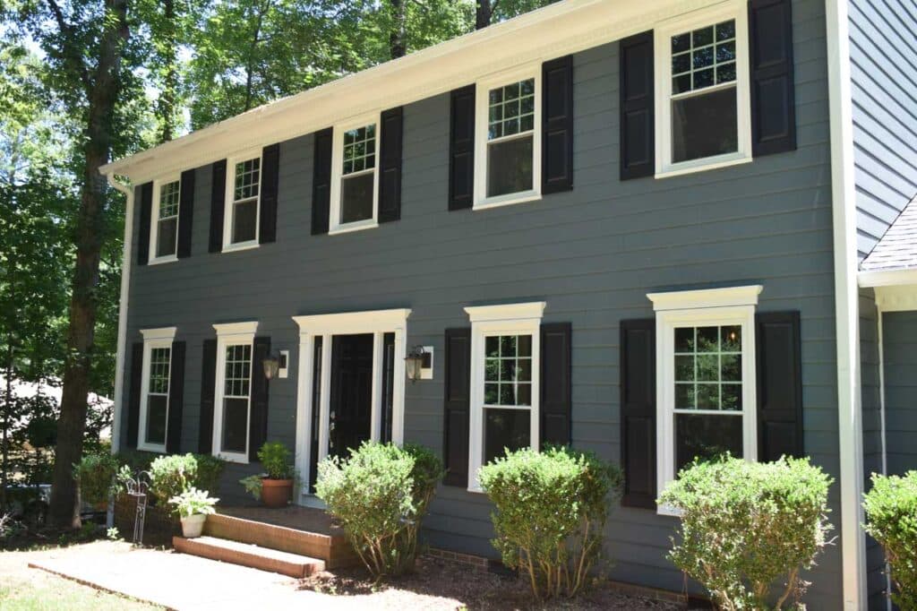 Dark blue fiber cement house siding and white window with black shutters