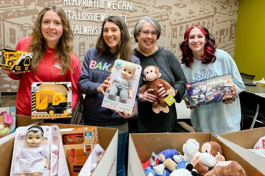 4 women holding toys to donate for children in need