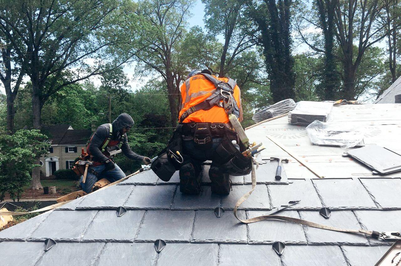 man in safety working on installing a slate roof