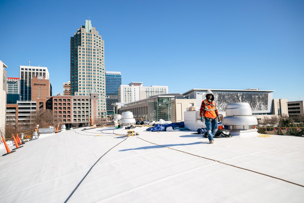 man in full safety walking on roof with skyline behind him