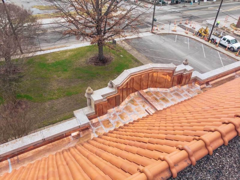 Orange clay tile roof and copper gutters on a historic brick church